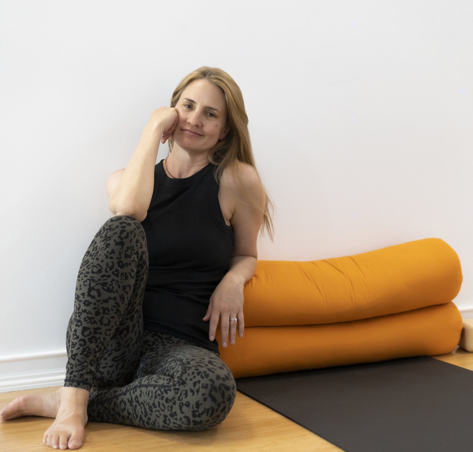 Renae Molden sitting in the Austin studio beside orange bolsters